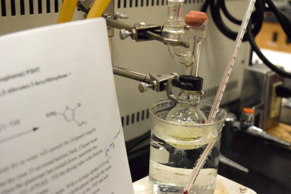 Close-up of a chemical reaction, with a white paper that describes the reaction in the foreground.