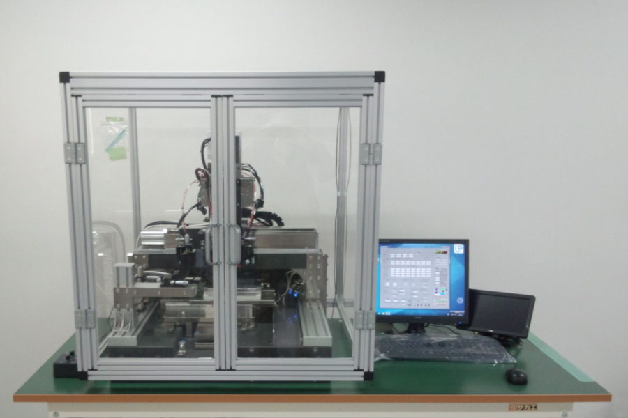 JCDREAM Printer Printing machinery enclosed in a glass box next to a desktop computer.