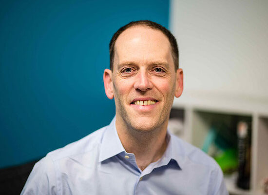 A man in a collared shirt smiles for the camera.