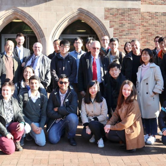 A group of students and teachers pose in front of a UW building.