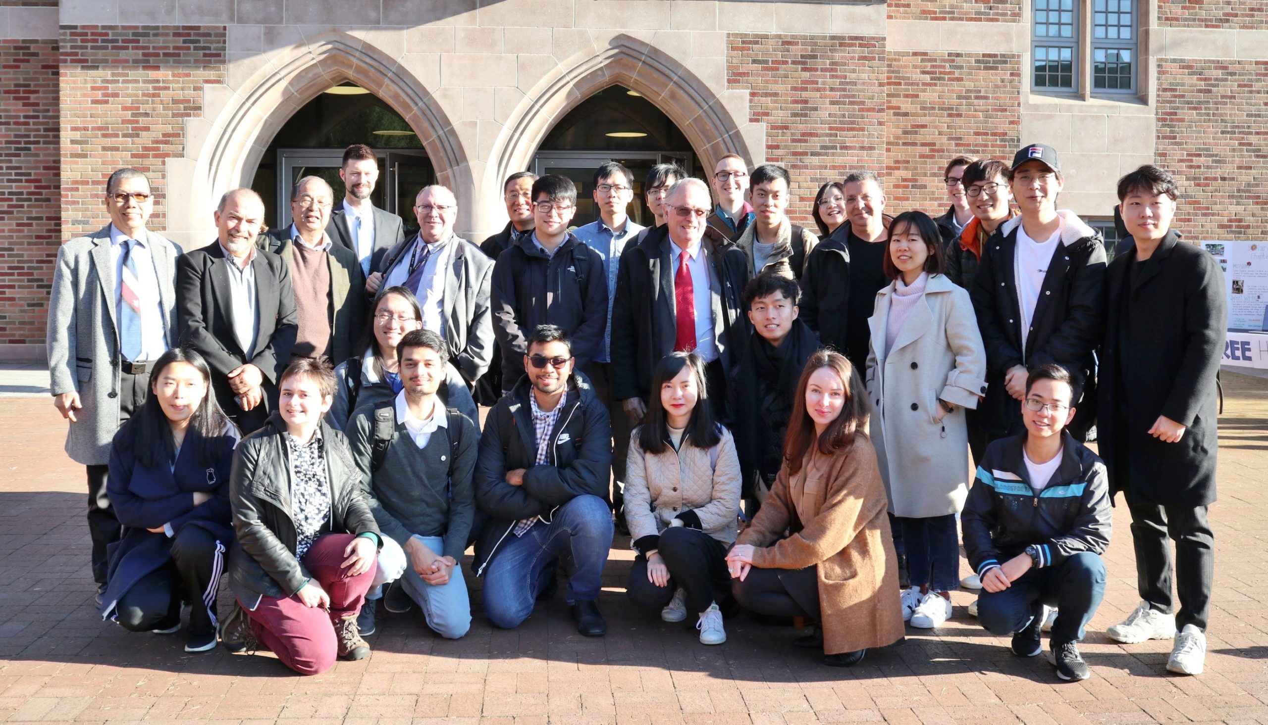 A group of students and teachers pose in front of a UW building.