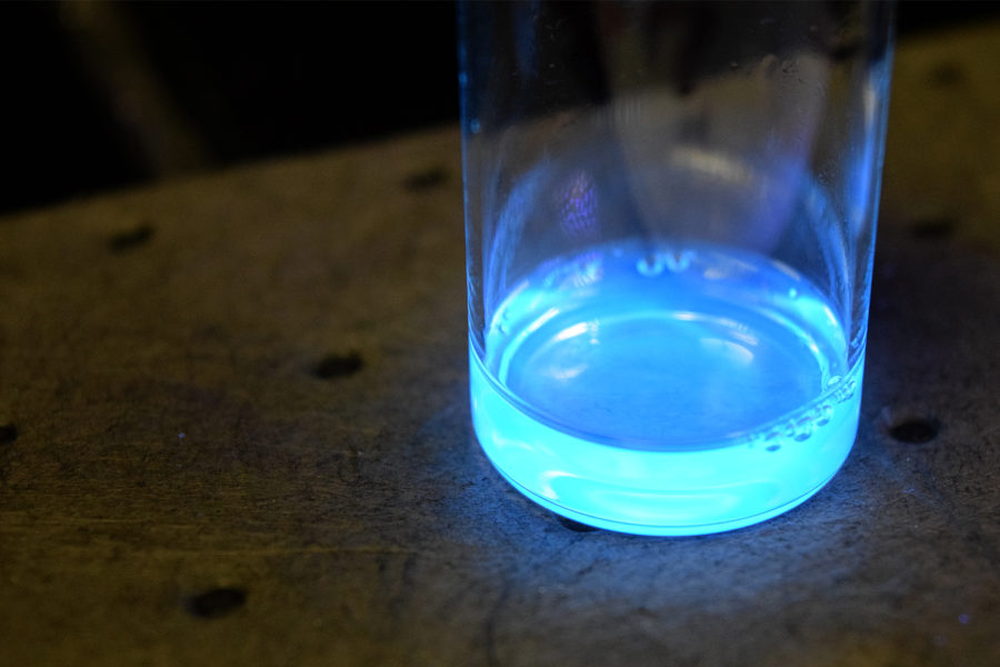 A close-up of a small container with a glowing blue liquid.