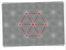 A microscope image of two-dimensional materials, with red dashed lines tracing out a hexagon with a central point. The vertices of the hexagon are aligned with lighter regions of the microscope image.