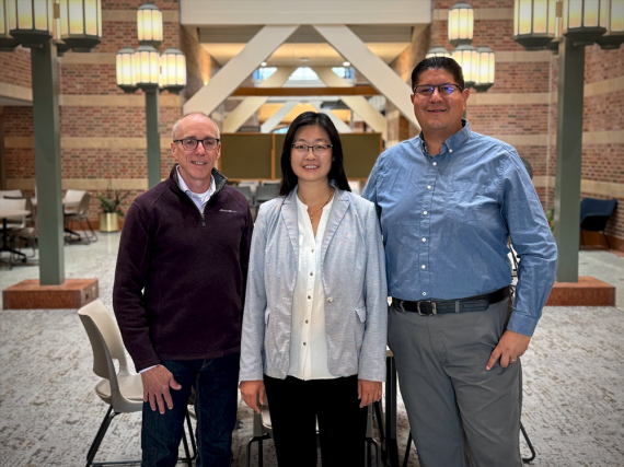Photo of three people standing together in a large open space