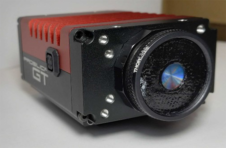A red and black prototype camera with a lense facing forward